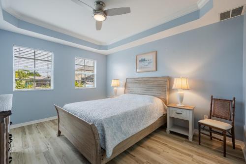 a bedroom with blue walls and a bed and a chair at Closest to the Pool! - Updated, Bright & Cheery - Condo Serenity Cove - Roelens Vacations in Cape Coral