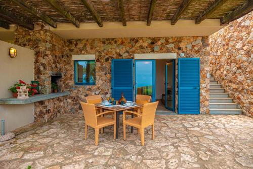 a patio with a table and chairs and a stone wall at Fattoria delle Ripalte in Capoliveri