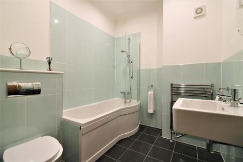 uma casa de banho com um lavatório, uma banheira e um WC. em Greenlees Clubhouse 3 Bed em Cambuslang