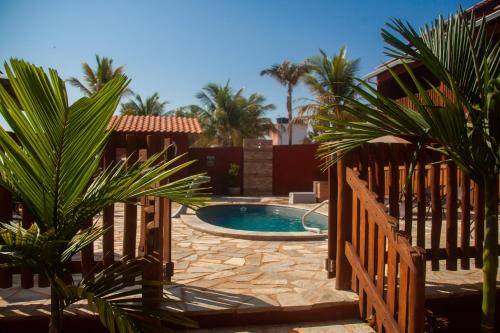 a pool in a yard with palm trees and a fence at Pousada Iandara in Pirenópolis