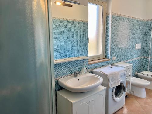 y baño con lavabo y lavadora. en Oliveri nuovo appartamento 5 posti letto più posto auto privato, en Oliveri