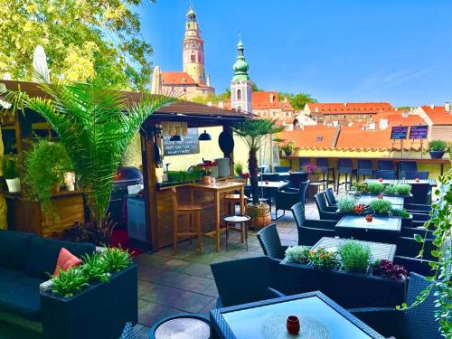 un patio en la azotea con mesas, sillas y plantas en Arcadie Hotel & Apartments, en Český Krumlov