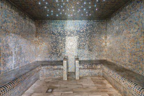 a tiled bathroom with a bench and a window at Cromer Country Club in Cromer