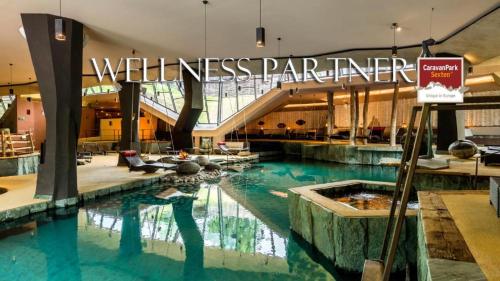 a swimming pool in a building with a wellness partner sign at Wachtler Dolomite Apartments in San Candido