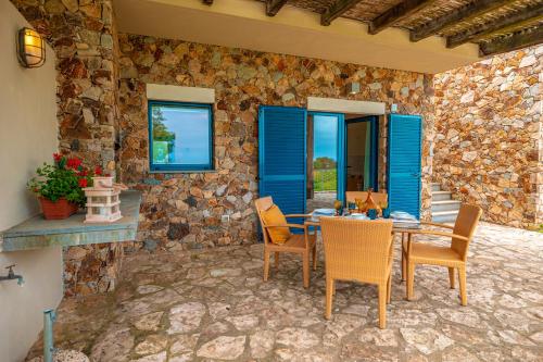 a patio with a table and chairs and a stone wall at Fattoria delle Ripalte in Capoliveri