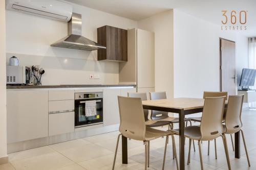 a kitchen with a wooden table and chairs at Wonderful marina 3BR home, with LUX interior w/AC by 360 Estates in Tal-Pietà