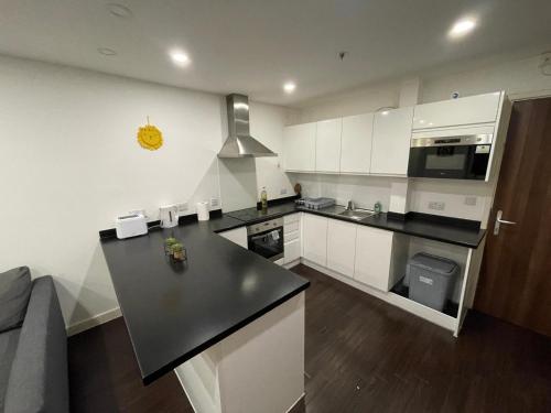 a kitchen with white cabinets and a black counter top at Amazing 1 Bedroom Flat in Essex TH104 in Basildon