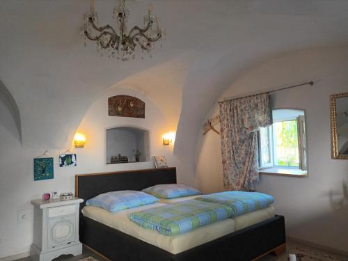 ヴィヒタッハにあるIm Gewölbe der Alten Druckereiのベッドルーム1室(ベッド1台、窓、シャンデリア付)