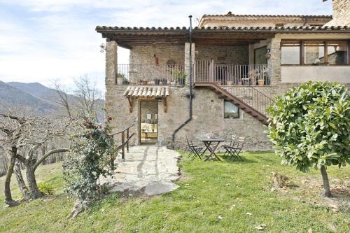 uma casa de pedra com uma mesa e uma varanda em Mas Regort em Vallfogona de Ripolles