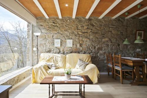 ein Wohnzimmer mit einem Sofa und einer Steinmauer in der Unterkunft Mas Regort in Vallfogona de Ripolles