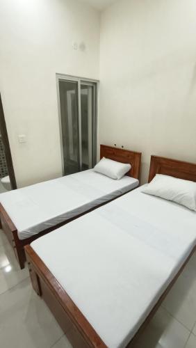 two beds in a room with white sheets at Continental Boys Hostel R-2 Johar Town in Lahore