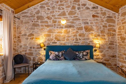 1 dormitorio con 1 cama azul en una pared de piedra en Villa Allegra Velici en Vižinada
