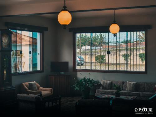 a living room with a couch and two windows at O Paturi - Village Hotel in Guaratinguetá