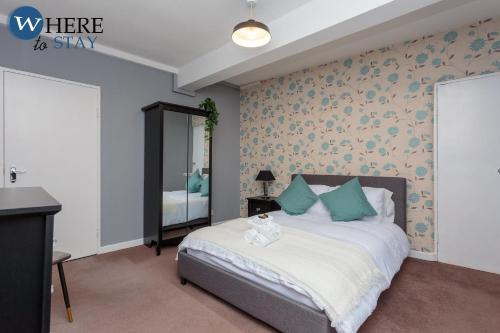 a bedroom with a bed with blue pillows and a mirror at Stunning 3 bedroom apartment Edinburgh in Edinburgh