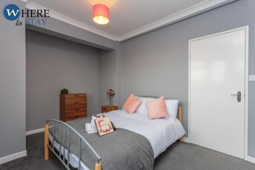 um quarto com uma cama com lençóis brancos e almofadas cor-de-rosa em Stunning 3 bedroom apartment Edinburgh em Edimburgo