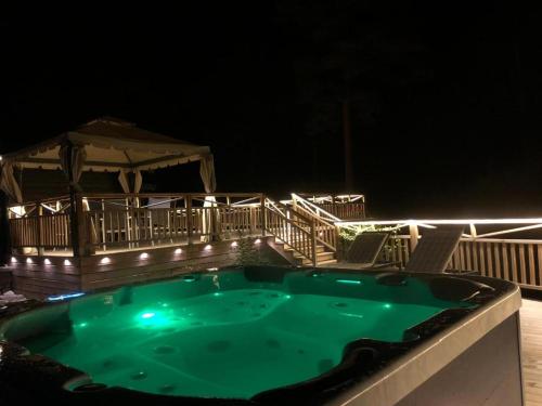a hot tub on a deck at night with lights at Timber cottages with jacuzzi and sauna near lake Vänern in Karlstad