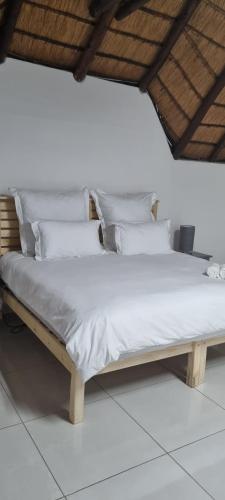 Una cama con sábanas blancas y almohadas. en LAPA ROOF, en Sandton