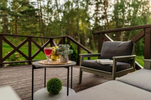 a table with a glass of wine and a chair on a deck at Close to nature - Nida Apartments in Nida