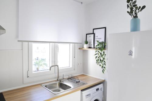 a white kitchen with a sink and a window at El Apartamento de Nueva in Cádiz