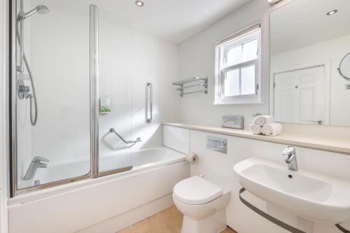 a white bathroom with a sink and a toilet and a shower at The Kenmore Club in Kenmore