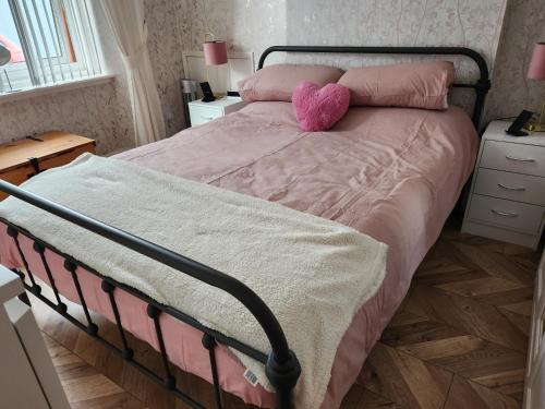 a bed with a pink comforter and a pink pillow at Largs holiday flat in Largs