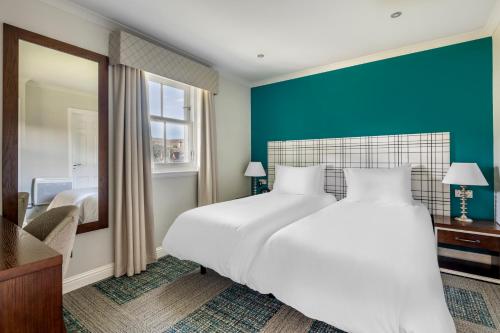 a bedroom with a large white bed and a mirror at The Kenmore Club in Kenmore