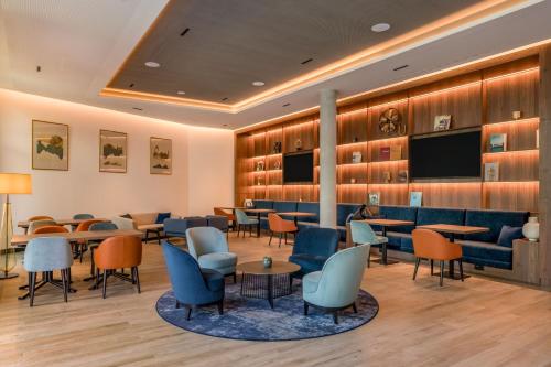 a waiting room with tables and chairs and a flat screen tv at Geneva Marriott Hotel in Geneva