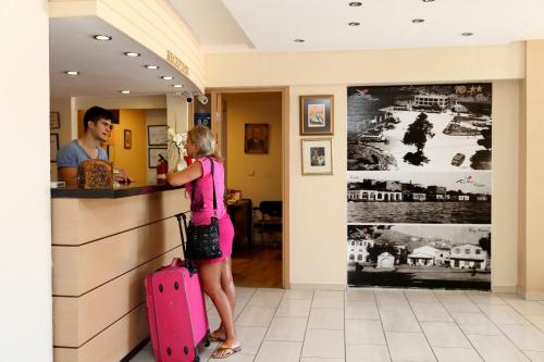 a woman standing at a counter with a pink suitcase at Rıdvan Hotel in Cesme