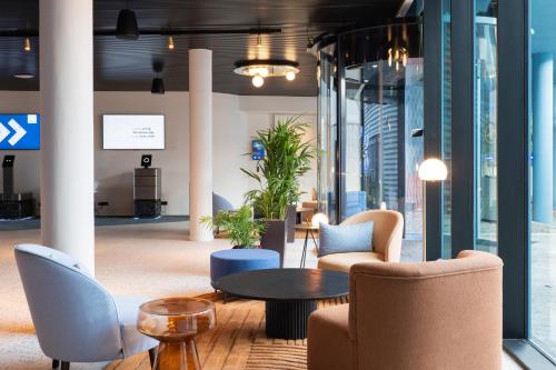 a lobby with chairs and a table in a building at voco Brussels City North by IHG in Vilvoorde
