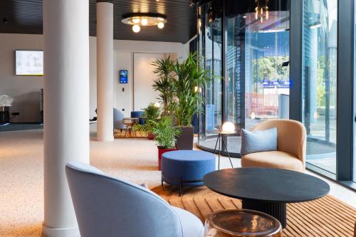 a lobby with tables and chairs and windows at voco Brussels City North by IHG in Vilvoorde