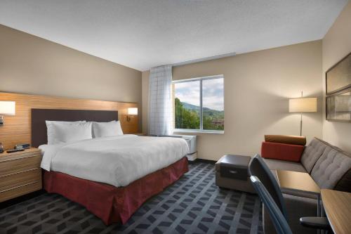 TownePlace Suites Boone في بون: غرفة فندقية بسرير كبير واريكة