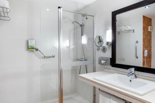 a bathroom with a shower and a sink and a mirror at Sunset Harbour Club in Adeje