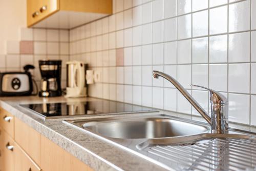 un fregadero de acero inoxidable en una cocina con azulejos blancos en Obertegghof Wohnung Schartenblick, en Sarentino