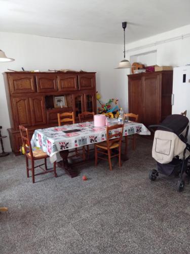 a dining room with a table and chairs and a table and a stroller at aurelie in Saint-Pierre-le-Moûtier