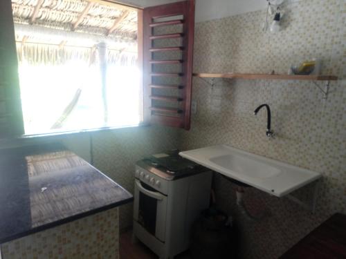 a kitchen with a sink and a stove and a window at Zion Land Canoa Quebrada in Aracati
