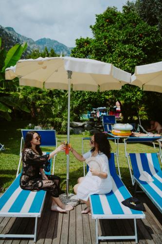 two women sitting on chairs under an umbrella at Hotel Limone in Limone sul Garda