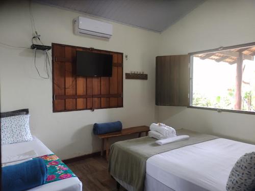 a bedroom with two beds and a tv on the wall at Pouso Divino dos Pireneus in Pirenópolis