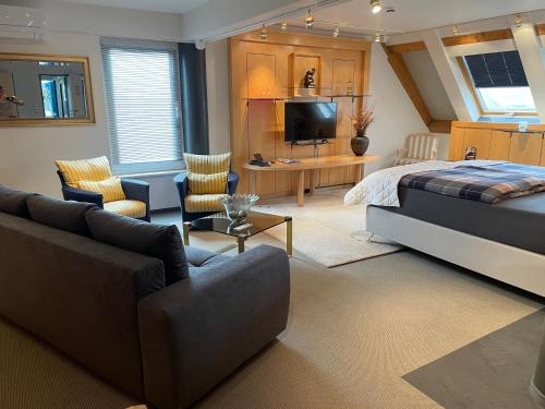 een slaapkamer met een bed, een bank en een tv bij SMC Muenster in Münster
