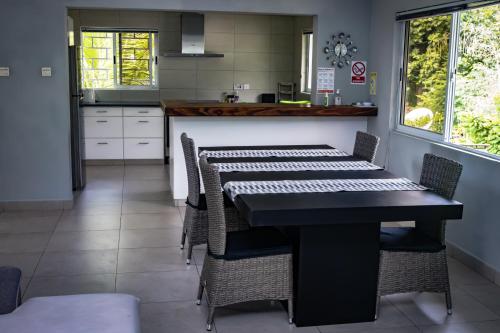 une salle à manger avec une table et des chaises ainsi qu'une cuisine dans l'établissement Riverside Residence - BEAU VALLON, à Beau Vallon