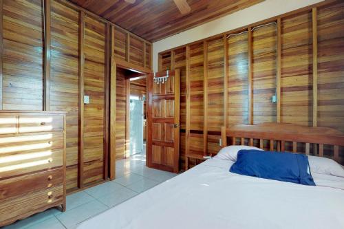 sypialnia z drewnianymi panelami ściennymi i łóżkiem w obiekcie Roughrider Inn Gold Standard Certified w Caye Caulker