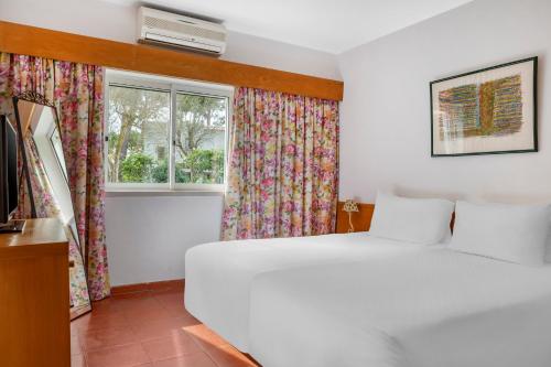 1 dormitorio con cama blanca y ventana en Vilar do Golf en Quinta do Lago