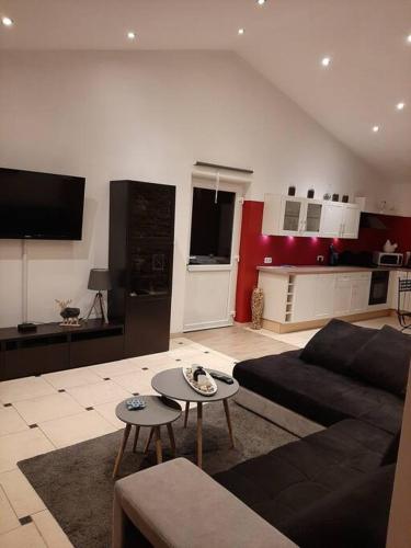 a living room with a black couch and a kitchen at Le calme de la prairie de liège in Liège