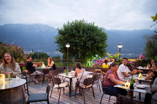 a group of people sitting at tables on a patio at Hotel Limone in Limone sul Garda