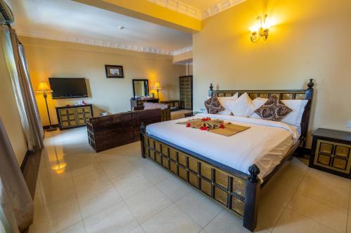1 dormitorio con 1 cama grande y TV en Golden Tulip Stone Town Boutique, en Zanzíbar