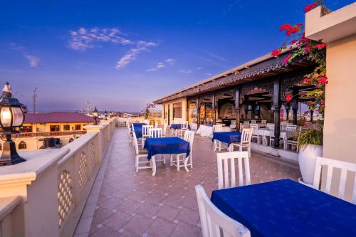 a restaurant with blue tables and chairs on a balcony at Golden Tulip Stone Town Boutique in Zanzibar City