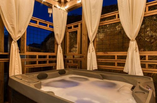 ガトリンバーグにあるMoonshiners Hideout Hot Tub Game Room Poolのカーテン付きの客室内のバスタブ
