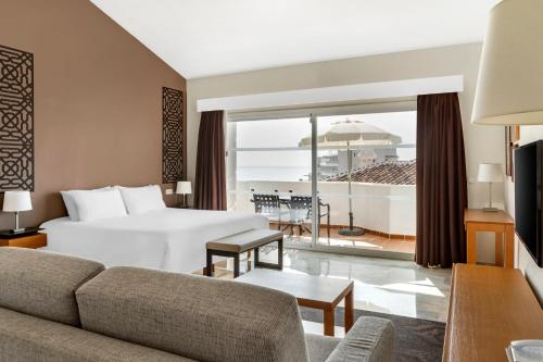 a hotel room with a bed and a view of the ocean at Sahara Sunset in Benalmádena