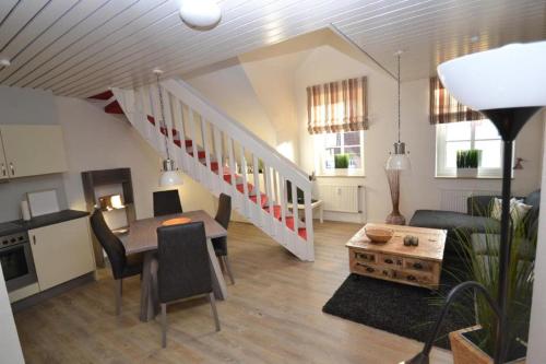 a living room with a table and a staircase at Tante Maaß in Flensburg