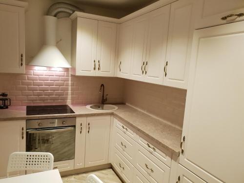 a kitchen with white cabinets and a sink at Ditemo center apartment self check in in Šiauliai