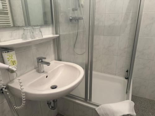 a white bathroom with a sink and a shower at Hotel Schuetzenhaus Vorsfelde in Wolfsburg